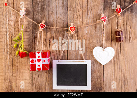 Red rose with gift box and white frame and chocolate on wooden background. Love concept. Stock Photo