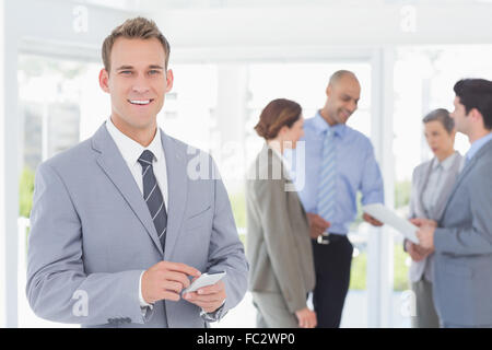 Businessman texting while his colleagues discussing Stock Photo