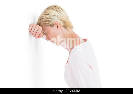 Nervous blonde woman leaning against the wall Stock Photo