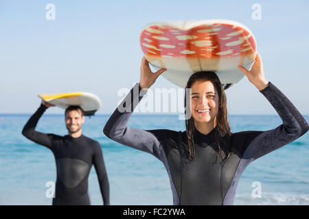 happy couple in wetsuits with surfboard on a sunny day Stock Photo