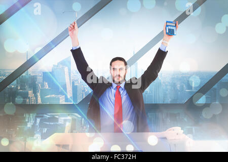 Composite image of businessman holding up reading glasses and calculator Stock Photo