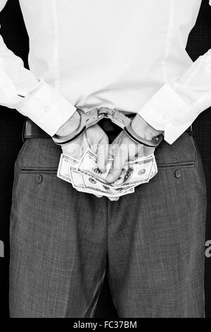 Composite image of businessman in handcuffs holding bribe Stock Photo