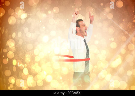 Composite image of happy businessman crossing the finish line and pointing up Stock Photo