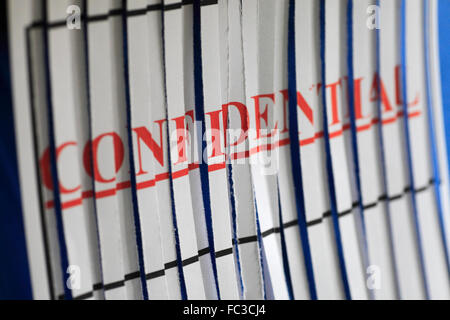 'CONFIDENTIAL' paper through a shredder. Stock Photo