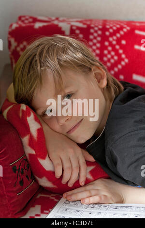 boy with book lying on sofa Stock Photo
