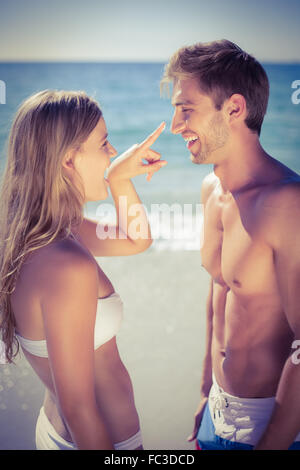 Pretty blonde putting sun tan lotion on her boyfriend Stock Photo