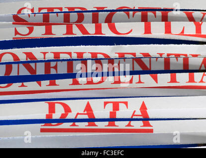 'STRICTLY CONFIDENTIAL DATA' paper through a shredder. Stock Photo