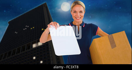 Composite image of happy delivery woman holding cardboard box and clipboard Stock Photo