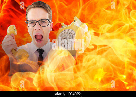 Composite image of geeky businessman shouting at retro phone Stock Photo