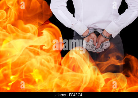 Composite image of businessman in handcuffs holding bribe Stock Photo