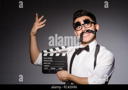 Young man with false moustache holding clapperboard isolated on Stock Photo