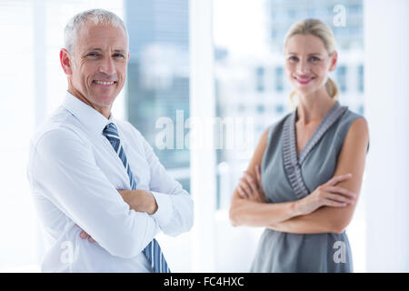 Two business people smiling at the camera in the office Stock Photo