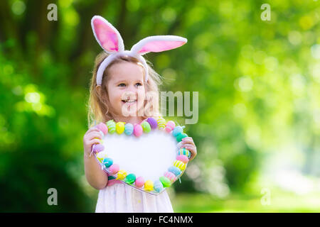 Little boy and girl having fun on Easter egg hunt. Kids in bunny ears and rabbit costume. Children with colorful eggs Stock Photo