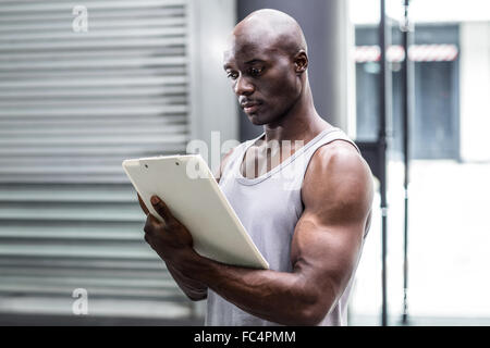Attentive muscular trainer writing on clipboard Stock Photo