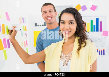 Portrait of smiling coworkers writing on sticky notes Stock Photo
