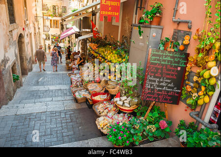 Mediterranean street, view in summer of a senior couple passing grocery shops in a narrow street off the Corso Umberto I in Taormina, Sicily, Italy Stock Photo