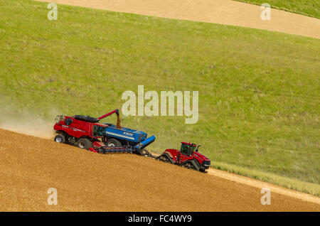 One or more combines offloading grain to a tractor pulled grain cart in ...