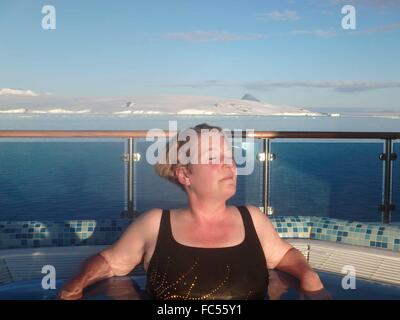 Woman relaxing in hot tub on cruise ship passing through the Antarctic Sound. Stock Photo