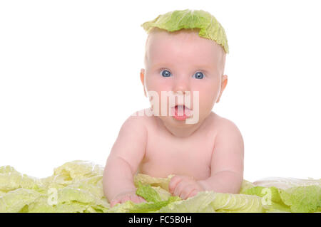 small child sitting among the cabbage leaves Stock Photo