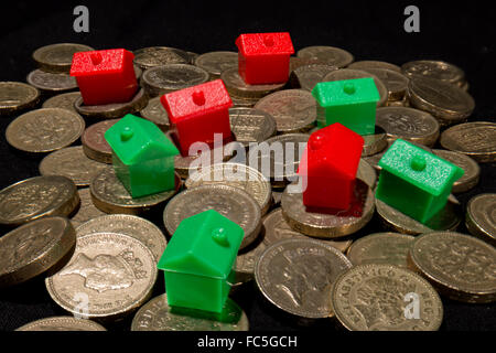 Red and green houses on a pile of British pound coins Stock Photo