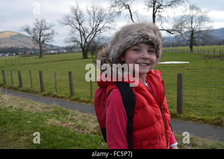 girl in a red coat with a fur hat and hood with a backdrop of the lake district cumbria Stock Photo