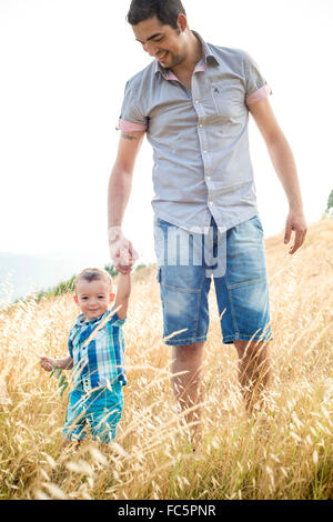 Smiling Man and Young Boy Walking Through Field Stock Photo