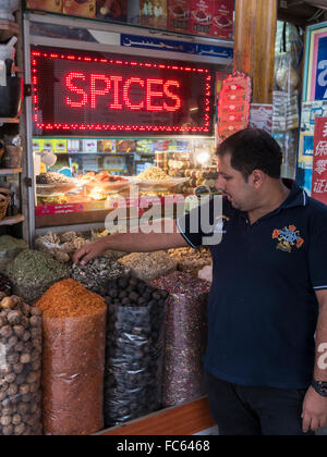 Dubai spice souk; trader fine tuning spice rack display. Stock Photo