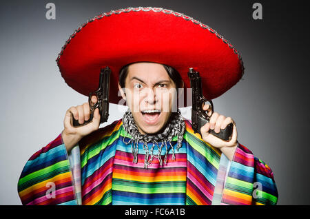 Man in vivid mexican poncho holding handgun against gray Stock Photo