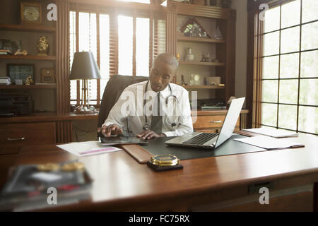 Black doctor using digital tablet in office Stock Photo