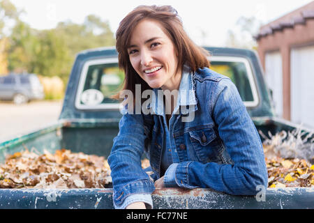 Hispanic woman sitting in truck bed Stock Photo