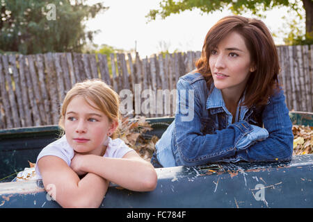 Mother and daughter sitting in truck bed Stock Photo