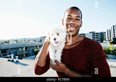 African American man holding dog on urban rooftop Stock Photo