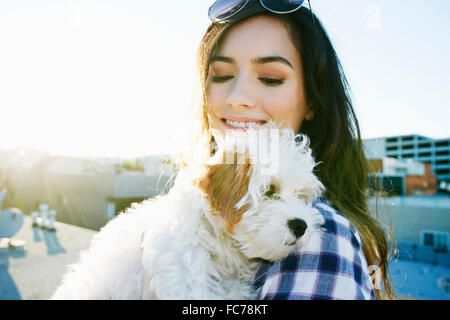 Mixed race woman holding dog on urban rooftop