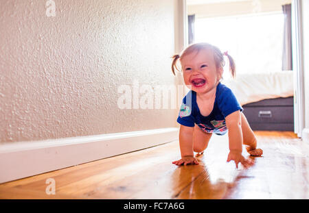 Caucasian baby girl crawling in hallway Stock Photo