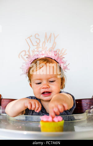 Caucasian baby girl eating birthday cupcake Stock Photo