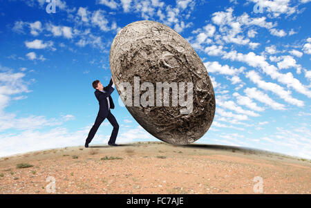 An image of a man rolling a rock uphill Stock Photo: 33940973 - Alamy