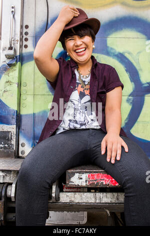 Asian woman sitting on graffiti truck Stock Photo