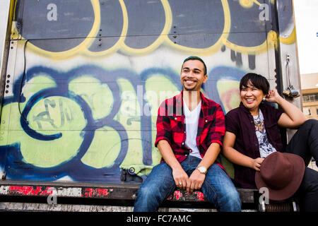 Couple sitting on graffiti truck Stock Photo