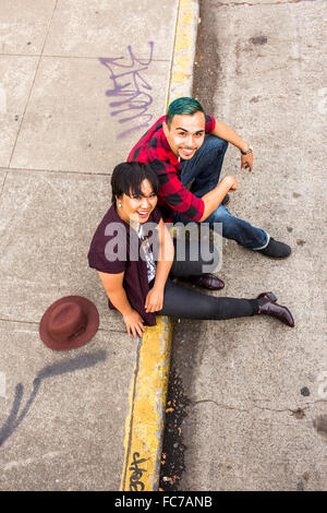 High angle view of couple sitting on curb Stock Photo