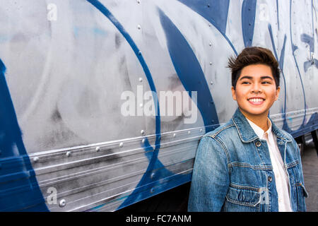 Young short hair Asian woman wearing sports bra and blue jeans standing  against a wall with graffiti and shadows, looking to the side into the  light Stock Photo - Alamy