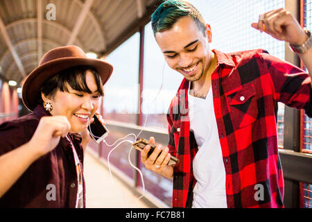 Couple sharing earphones to listen to music Stock Photo
