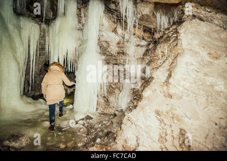 Caucasian woman exploring stalactites in cave Stock Photo