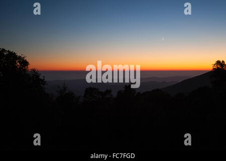 Sunset sky over silhouette of remote mountains Stock Photo