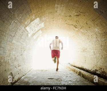 Caucasian man jogging in tunnel Stock Photo