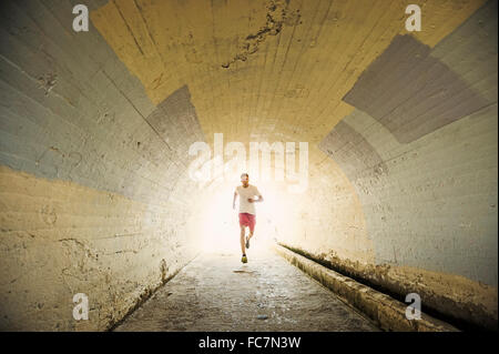 Caucasian man jogging in tunnel Stock Photo