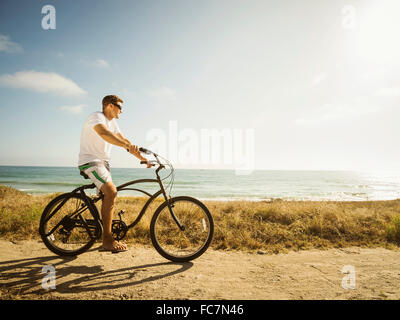 Caucasian man riding bicycle on beach Stock Photo