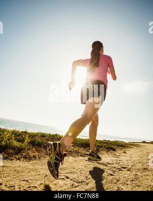 Caucasian woman jogging on dirt path Stock Photo