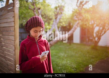 Mixed race girl using cell phone in backyard Stock Photo