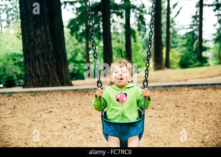 Caucasian girl playing on swing Stock Photo