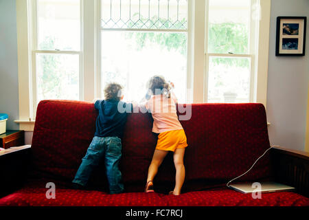 Caucasian children standing on sofa Stock Photo